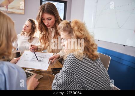 Female colleagues discussing architectural plan in office Stock Photo