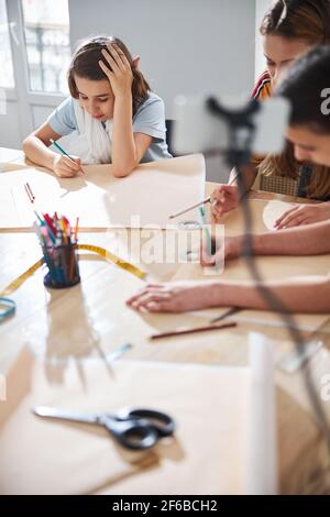 Adorable female kids drafting sewing patterns in workshop Stock Photo