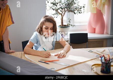 Adorable little seamstress making sewing pattern in workshop Stock Photo