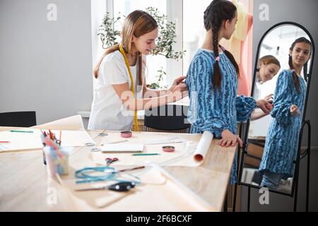 Adorable girls trying on dress in sewing workshop Stock Photo