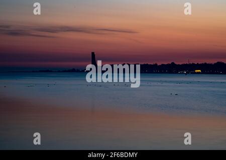 Kiel, Germany. 31st Mar, 2021. The sun rises behind the naval memorial in Laboe on the Kiel Fjord. Credit: Axel Heimken/dpa/Alamy Live News Stock Photo