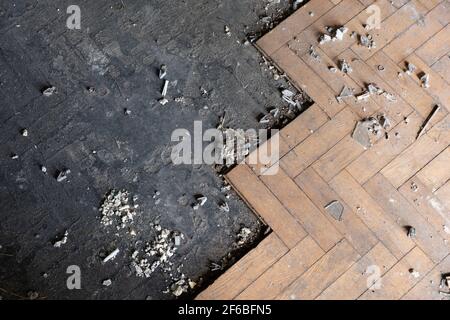 Parquet wooden flooring, dirty old floor, half of it covered with wood planks in an abandoned building room Stock Photo
