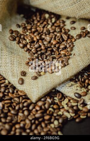 Roasted and green coffee beans on burlap closeup. Coffee beans background. Stock Photo
