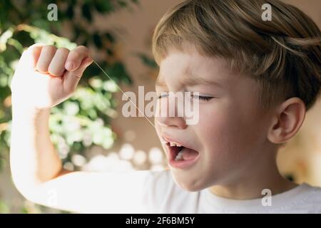 Portrait of little boy upset teeth pain. tries to remove his baby tooth Stock Photo