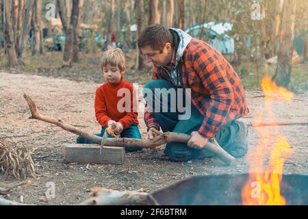 Father and son cutting log  with wood saw for a camp fire in the forest, Kuitpo, South Australia Stock Photo