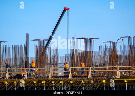 Builders walking on bridge near unfinished building Stock Photo