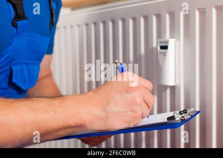 Technician reading the heat meter to check consumption Stock Photo