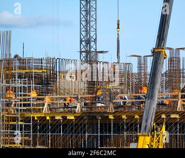 Builders walking on bridge near unfinished building Stock Photo