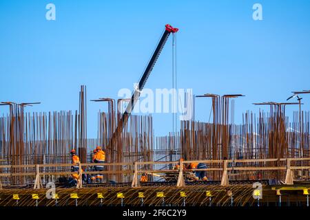 Builders walking on bridge near unfinished building Stock Photo