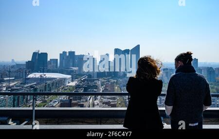 Back view of two females looking at Paris cityscape from lookout terrace. Skyscrapers at La Defense financial center. Stock Photo