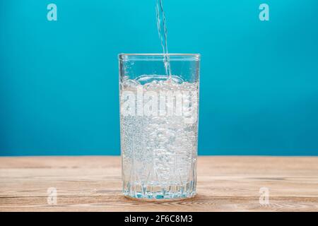 Pure fresh carbonated water with bubbles in a glass on a blue background Stock Photo