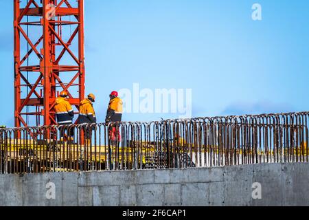 Builders walking on bridge near unfinished building Stock Photo