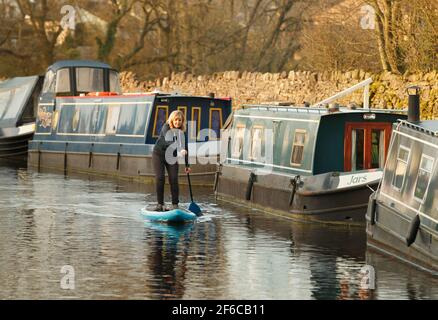 Joanna Moseley, the first woman to paddleboard along the 162-mile Canal and River Trust Coast-to-Coast Trail, pledges her support for Canal and River Trust's Plastics Challenge, as she paddleboards at the Greenberfield Locks near Barnoldswick, Lancashire. Picture date: Wednesday March 31, 2021. Stock Photo