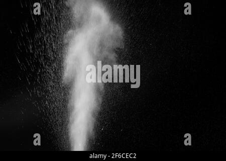 Curly white steam rising up and splashing water scattering in different directions isolated on a black background. Can be used as background, design e Stock Photo