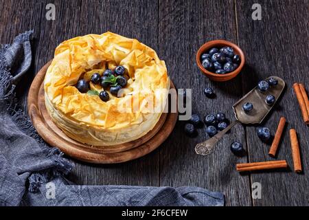 Layered Apple Blueberry Pie With Phyllo Crust on a dark rustic wooden table, horizontal view from above, flat lay Stock Photo