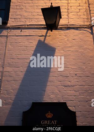 Shadow of an unlit lantern thrown from another, more modern light source out of sight in Westbury, Wiltshire, England, UK. Stock Photo