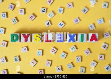 wooden alphabet blocks with DYSLEXIA word in the center on yellow background. Concept of Dyslexia awareness and human brain development Stock Photo