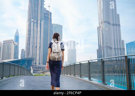 Young beautiful woman enjoying the view of Dubai downtown. Enjoying travel in United Arabian Emirates. view from the back or rear view, the lady walks Stock Photo