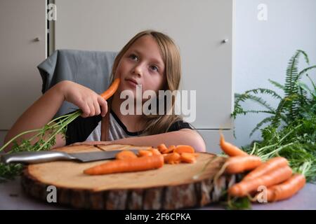 Little girl cuts fresh carrots in the kitchen Stock Photo