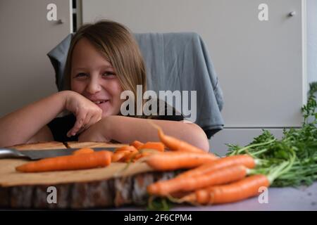 Little girl cuts fresh carrots in the kitchen Stock Photo