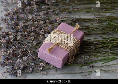 Handmade soap with natural ingredients and dry lavender flowers on a gray concrete background. Close up. Stock Photo