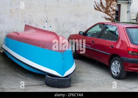 Car and boat on parking place near grey wall of Saint-Pierre Quiberon beach Stock Photo