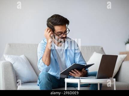 Young Arab Freelancer Guy Checking Working Schedule In Planner Notepad At Home Stock Photo