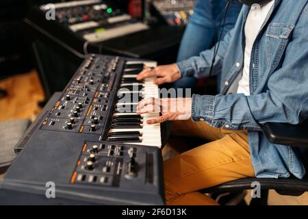 Stock photo of unrecognized musician in professional music studio playing electronic piano keyboard. Stock Photo