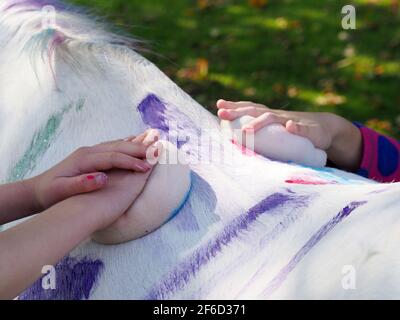 Close up of children decorating a pony with animal friendly paint and chalk. Stock Photo