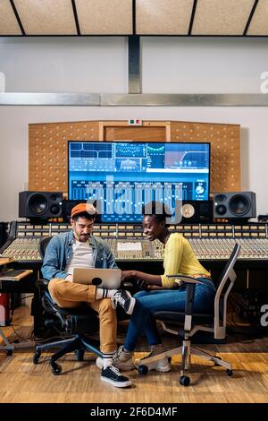 Stock photo of male music producer working with black singer in professional music studio. Stock Photo