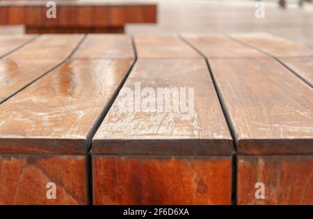Surface of varnished wooden timbers. A park bench made of wood. Fragment of a street bench with scratched surface. Stock Photo