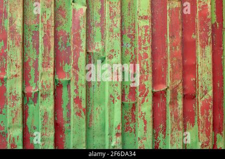 Corrugated metal cladding surface, painted in green and red. Old scratched green, red colour metal plate Stock Photo