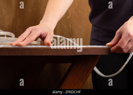 LED strip installation,adhesive diode tape is attached to the table Stock Photo