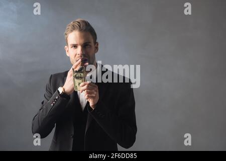 successful businessman lighting cigar with burning dollar banknote on grey background with smoke Stock Photo