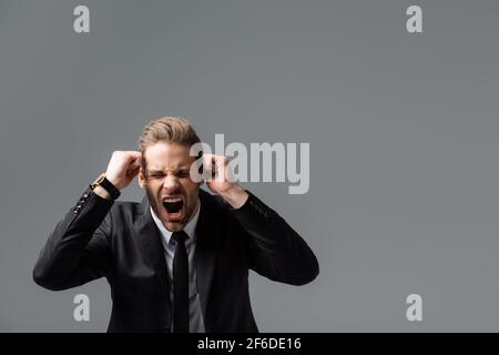 angry businessman showing clenched fists and shouting isolated on grey Stock Photo