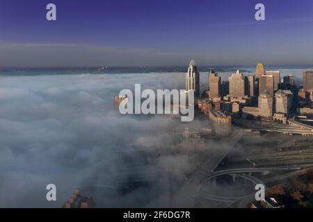 Early morning fog blankets the Ohio River over downtown Cincinnati and Kentucky as the sun illuminates buildings and bridges through the clouds of fog Stock Photo
