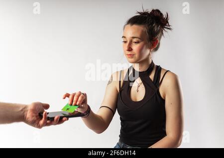 Alternative young woman with tattoos paying with her contactless credit card via mobile phone Stock Photo