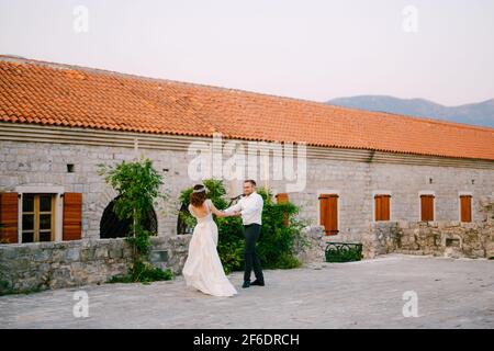 The bride and groom whirl, holding hands, near the church in the old town of Budva  Stock Photo