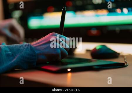 Male Video Editor hand Works with Footage or Video on His graphic panel of Personal Computer, he Works in Creative Office Studio or home. Neon lights Stock Photo
