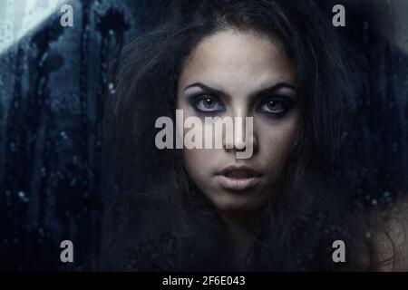 Dark witch behind the wet glass Stock Photo