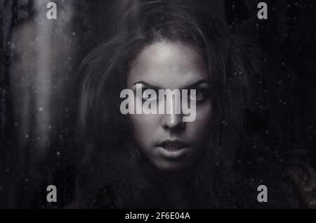 Dark witch behind the wet glass Stock Photo