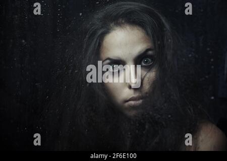 Dark witch behind the wet glass Stock Photo