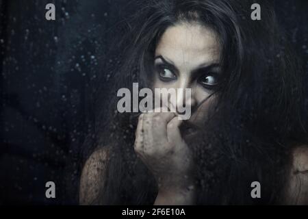 Dark witch behind the wet glass Stock Photo