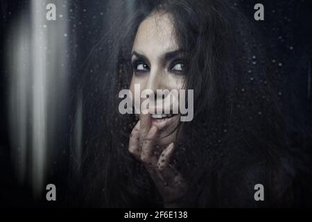 Dark witch behind the wet glass Stock Photo