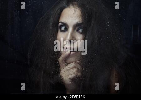 Dark witch behind the wet glass Stock Photo