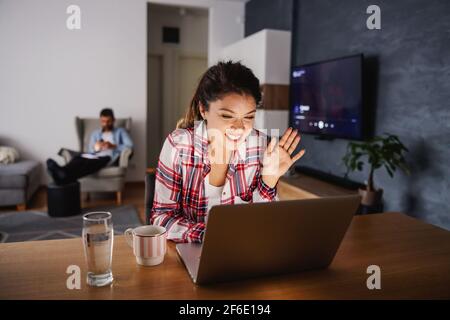 Smiling happy woman sitting at home during lockdown and having video call with her loved ones. Stock Photo