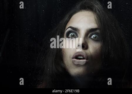 Dark witch behind the wet glass Stock Photo