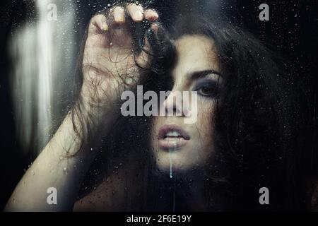 Dark witch behind the wet glass Stock Photo