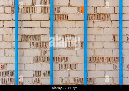 Texture of gray brick painted wall and four blue pipes, industrial background Stock Photo