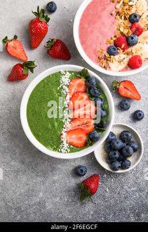 Matcha green tea breakfast superfoods smoothies bowl topped with strawberries, blueberries, coconut flakes Overhead, top view, flat lay Stock Photo